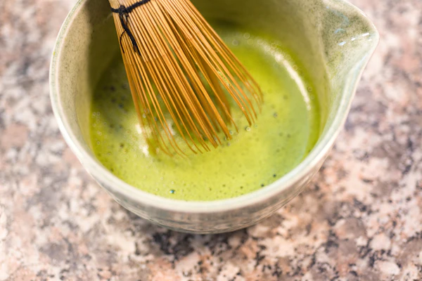 Matcha tea ceremony preparation with bamboo whisk