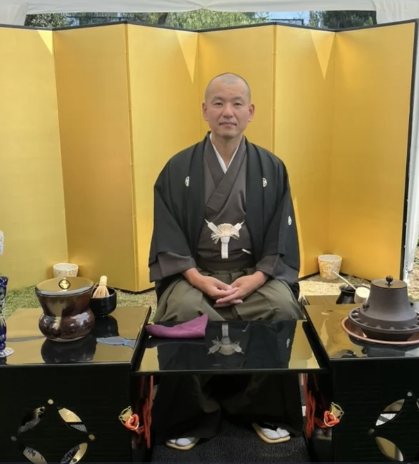 Traditional tea ceremony master in formal kimono with golden screen